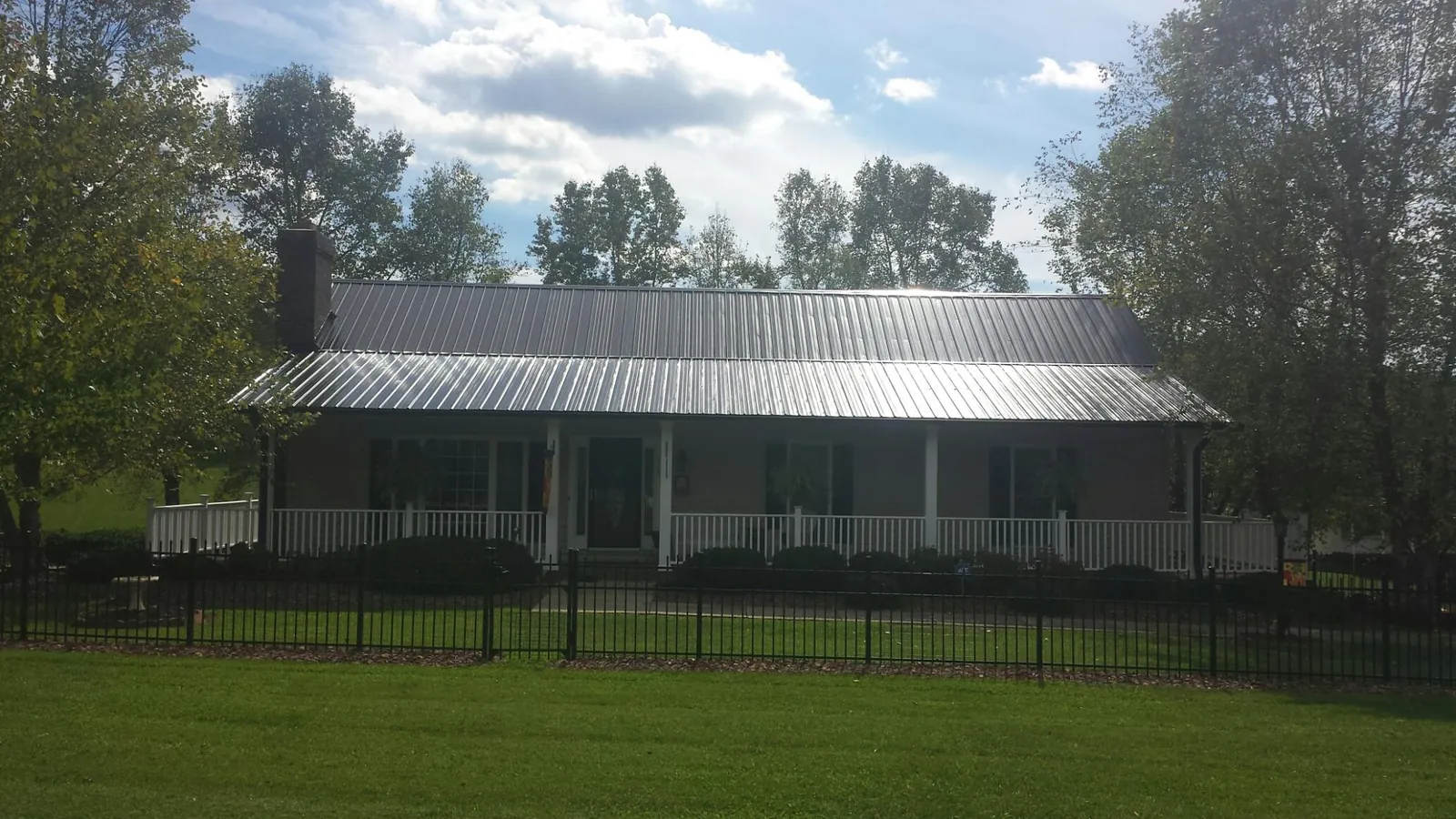 Gray metal roof on a brick ranch with a full width front porch — Gutter Guard Installation work by our crew in Seymour